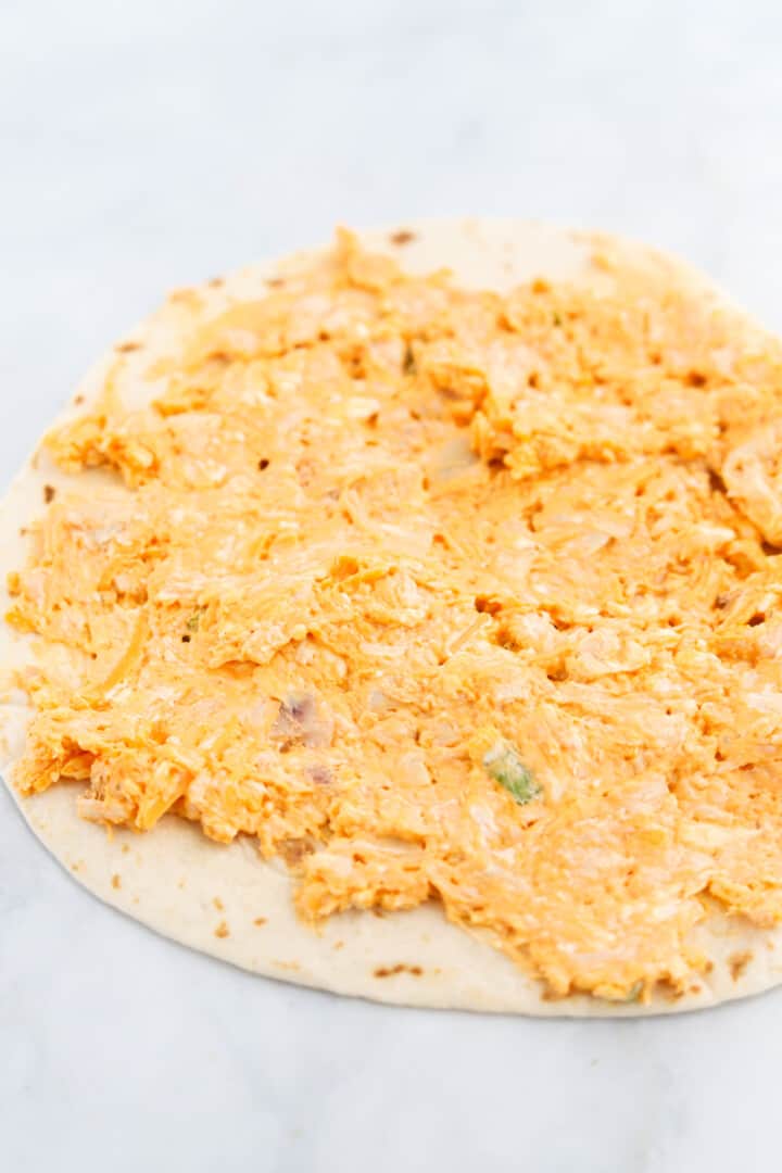 spreading the buffalo chicken mixture on to the tortilla.