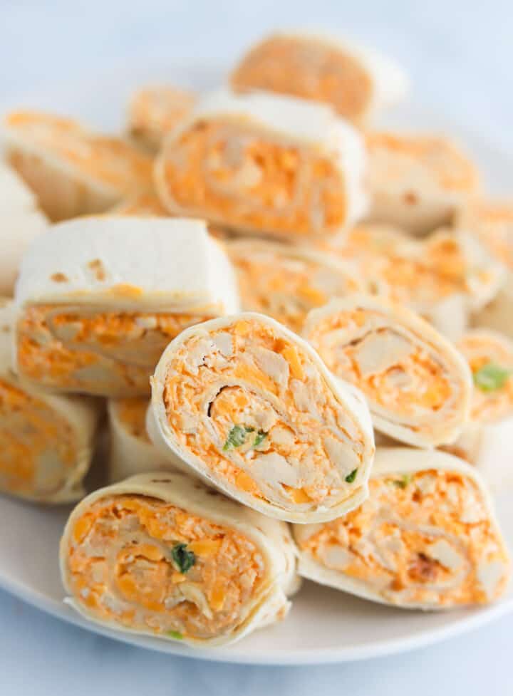 Buffalo Chicken Pinwheels stacked on white serving plate.