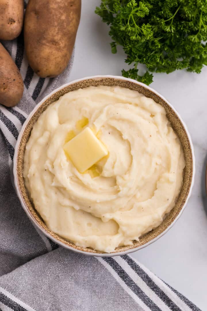 topview of buttermilk mashed potatoes with a slice of butter on top.