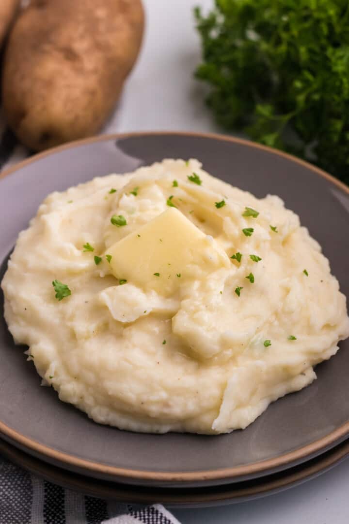 mashed potatoes on a plate with a slice of butter.