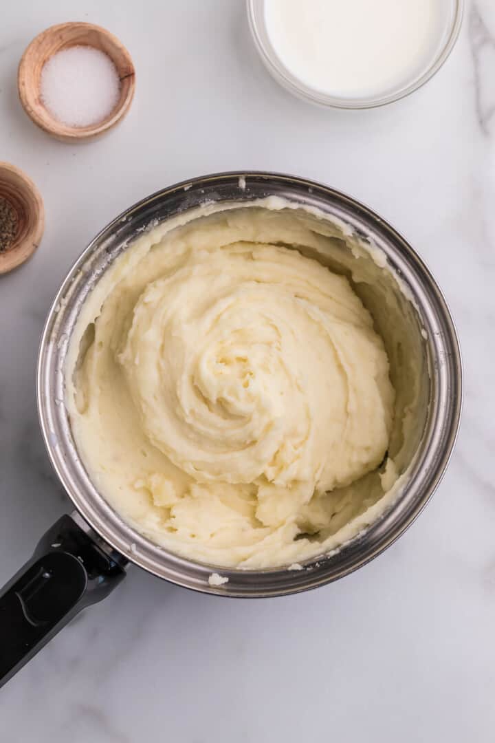 mashing the potatoes until they are creamy.