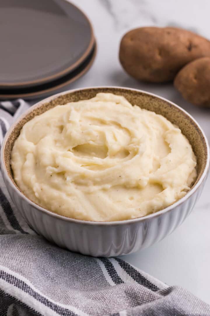serving the mashed potatoes in a white bowl.