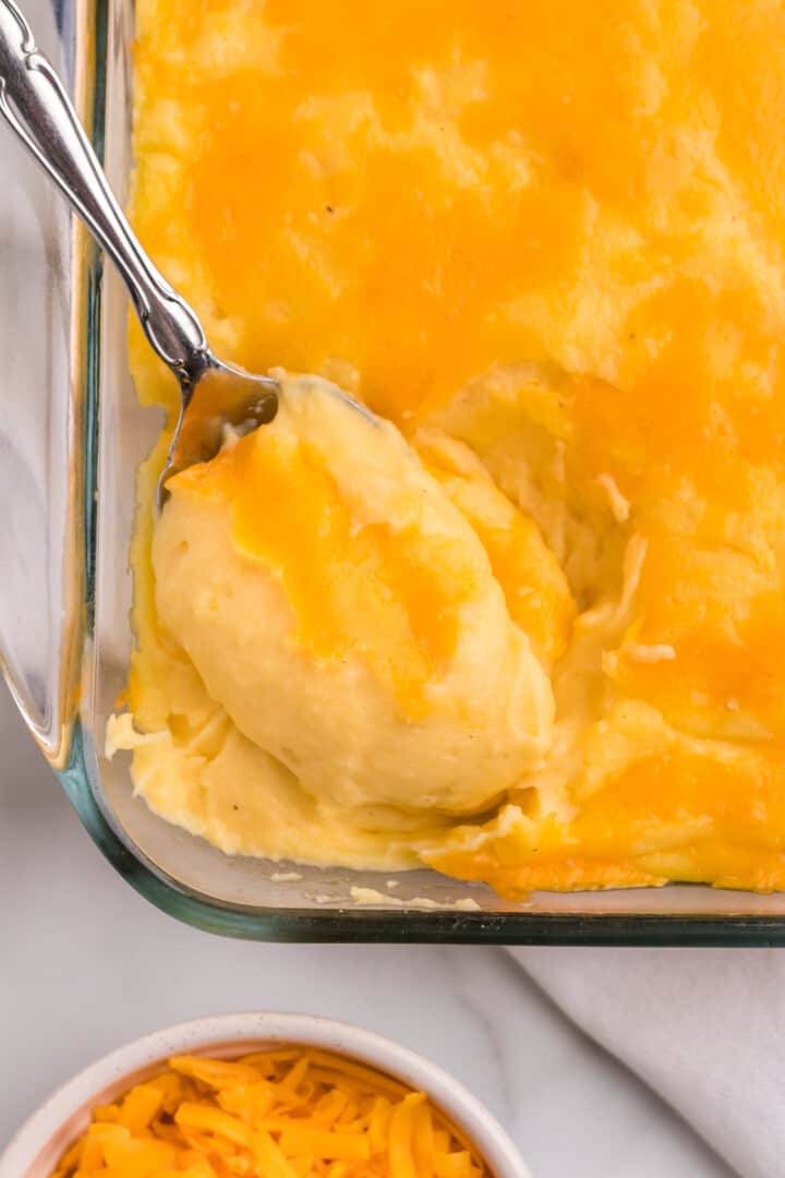 serving the cheesy mashed potatoes with a silver spoon.