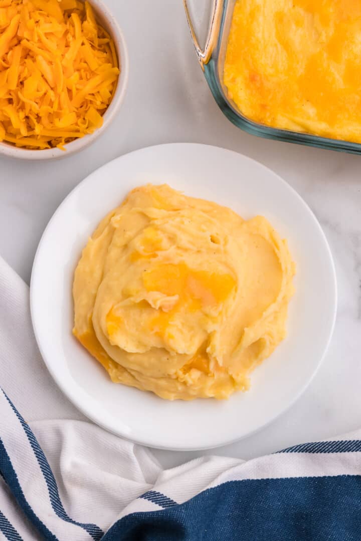 closeup of cheesy mashed potatoes on white plate.