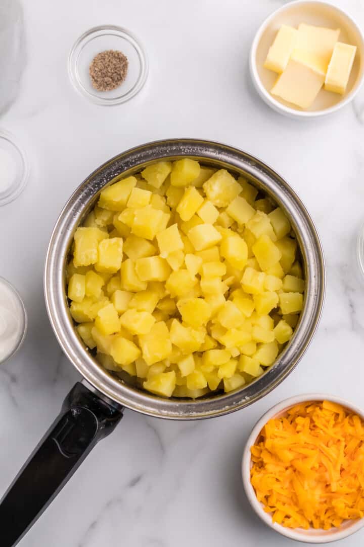 potatoes boiled in large pot with other ingredients in the background.