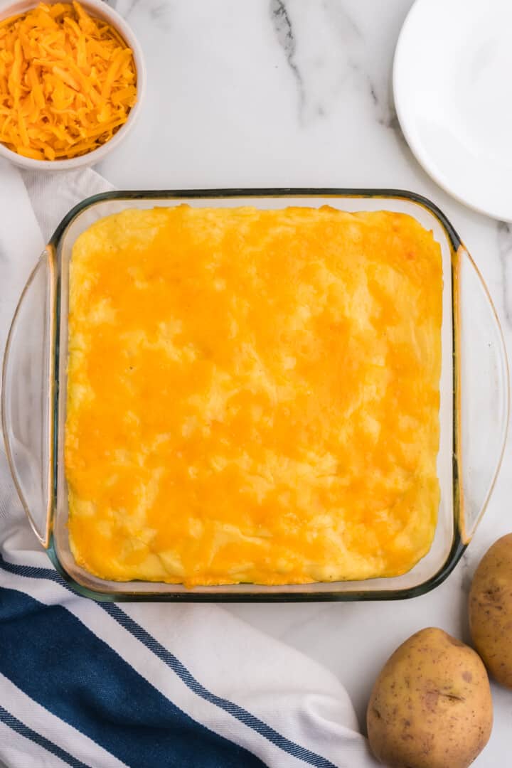 pouring the mashed potatoes into a baking dish.