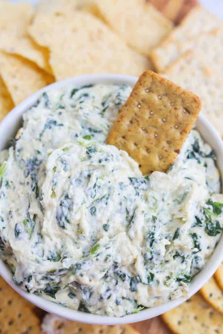 Cheesy Spinach Dip in white serving dish with crackier.