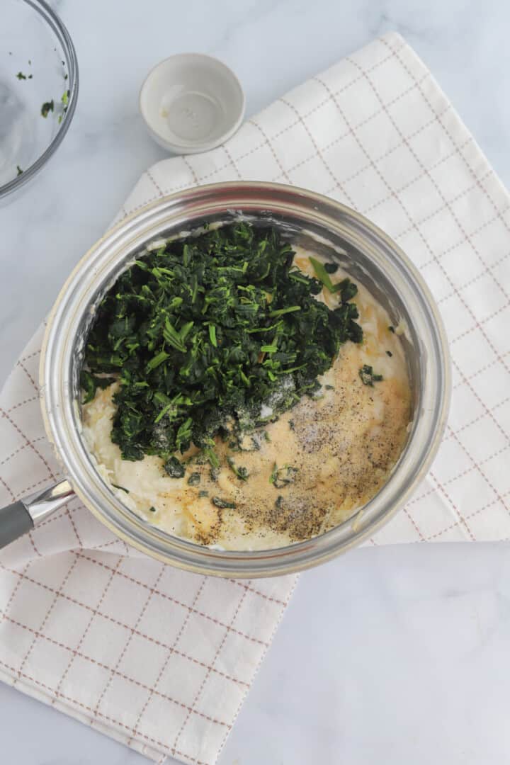 adding the spinach and spices to the saucepan.