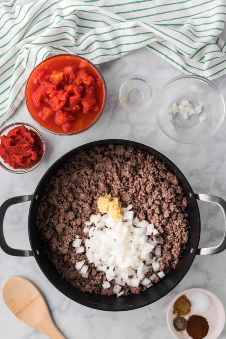 ground beef cooked with onions and garlic and remaining ingredients around the pot.