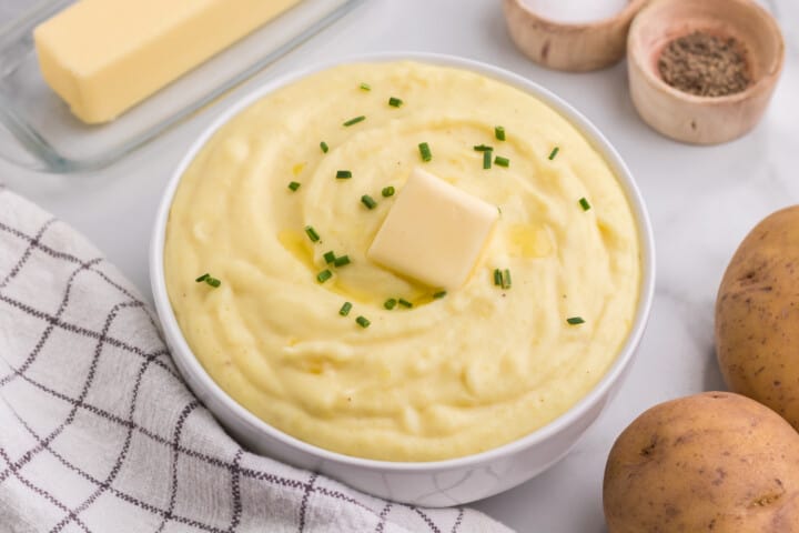 Cream Cheese Mashed Potatoes with slab of butter on top in serving bowl.