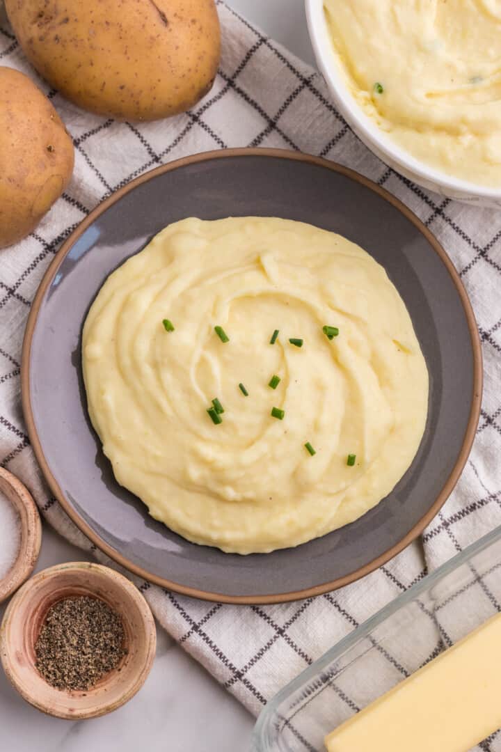cream cheese mashed potatoes on plate with chives on top.