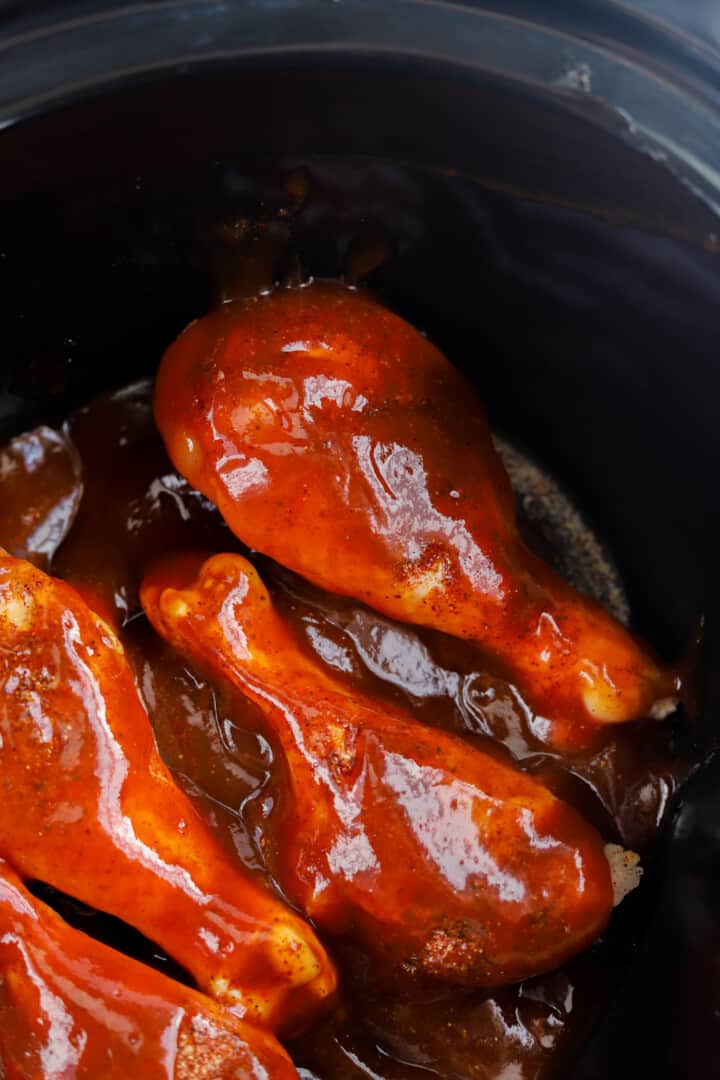 closeup of chicken leg covered in BBQ sauce in slow cooker.
