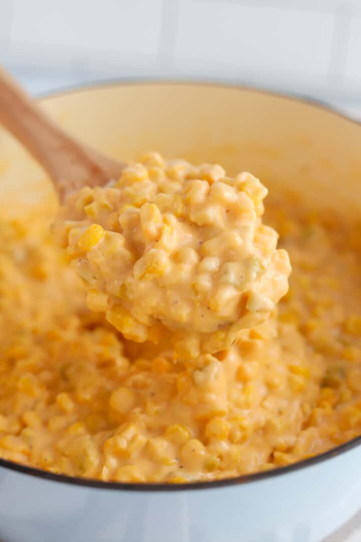 Cheesy Corn in large pot served with wooden spoon.