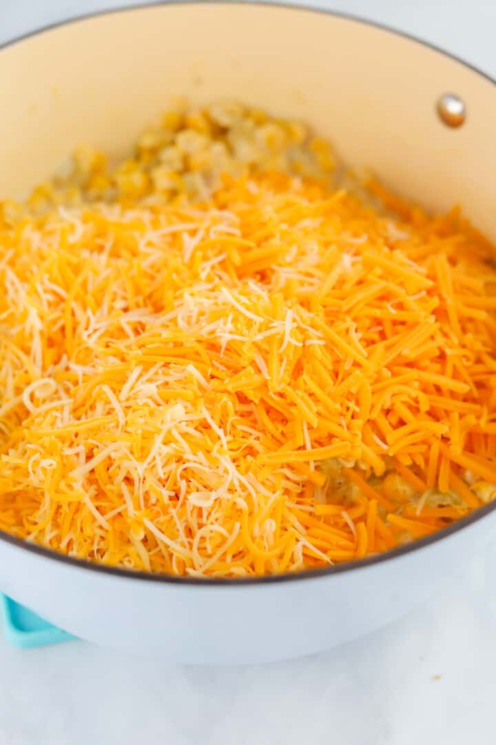adding the shredded cheeses to the pot.