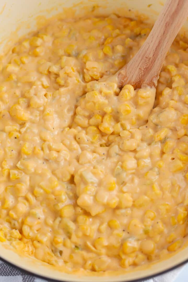 mixing the Cheesy Corn with a wooden spoon.