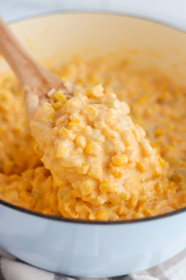 closeup of Cheesy Corn on wooden spoon.