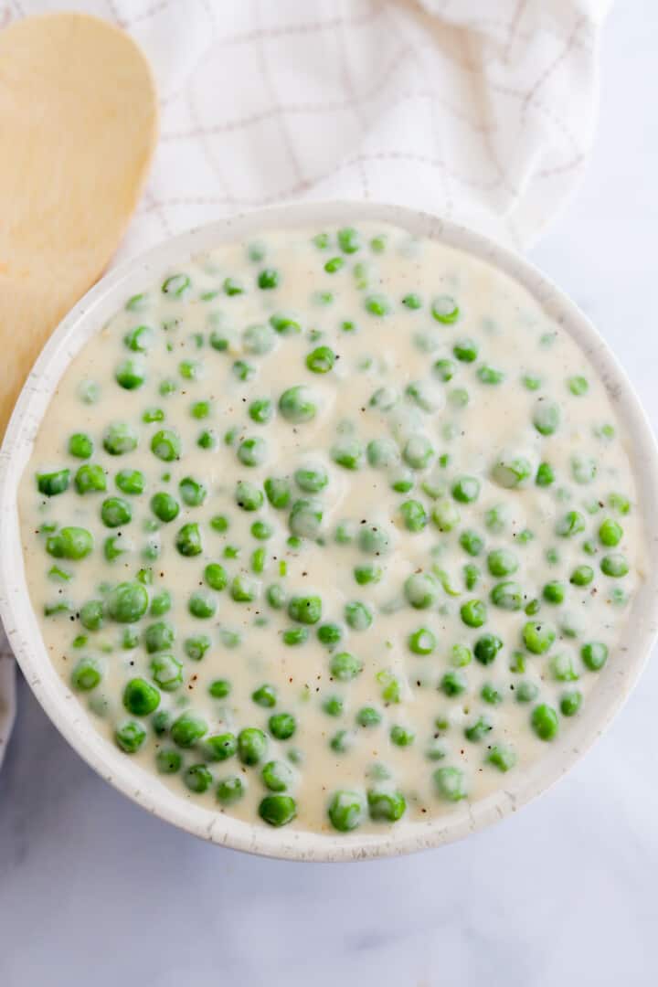 top view of the creamed peas in a white bowl.