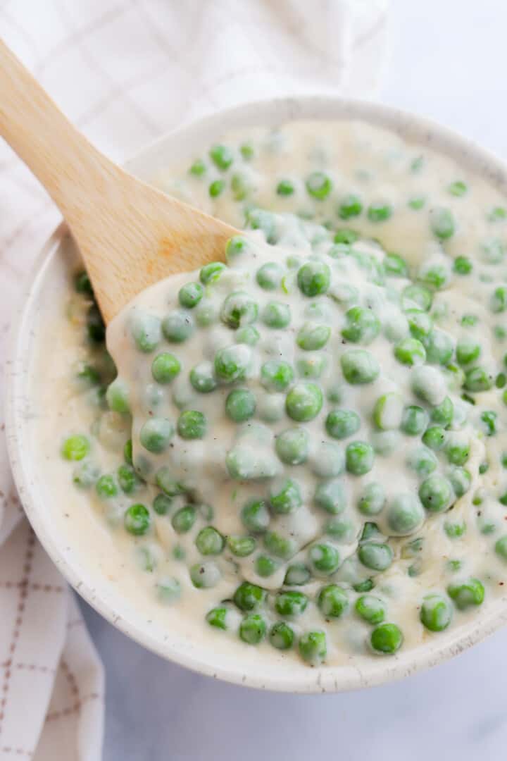 using wooden spoon to serve the creamed peas.