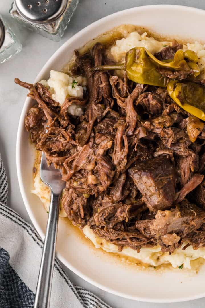 Mississippi Pot Roast on white plate on top of mashed potatoes.