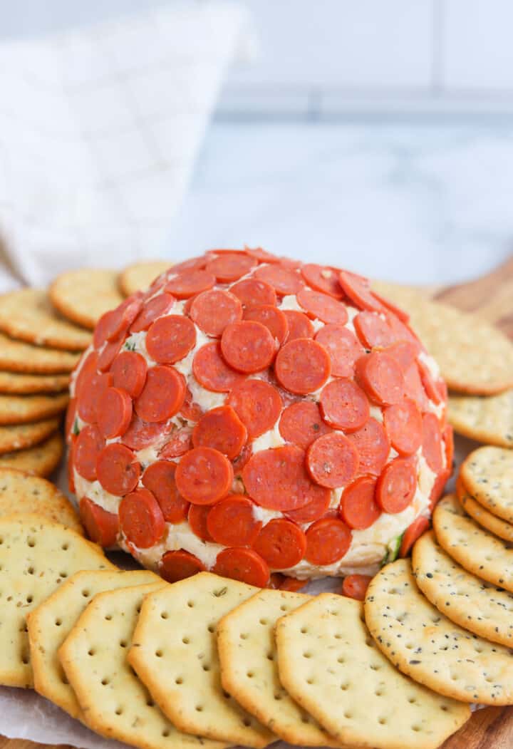 Pepperoni Cheese Ball on serving plate with crackers around it.