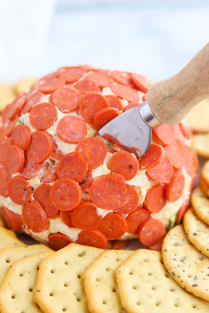 using a knife to serve the cheese ball.