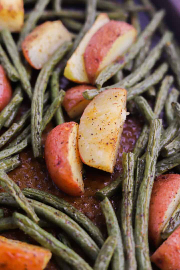 closeup of potatoes and green beans on the baking sheet.