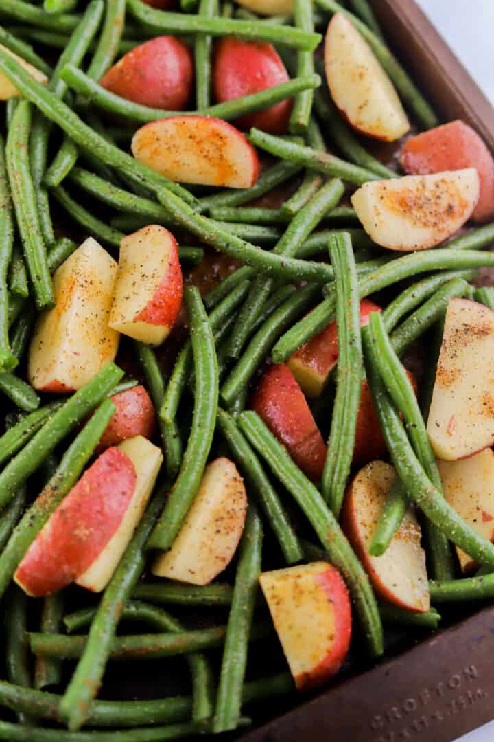 seasoned green beans and potatoes on baking sheet.