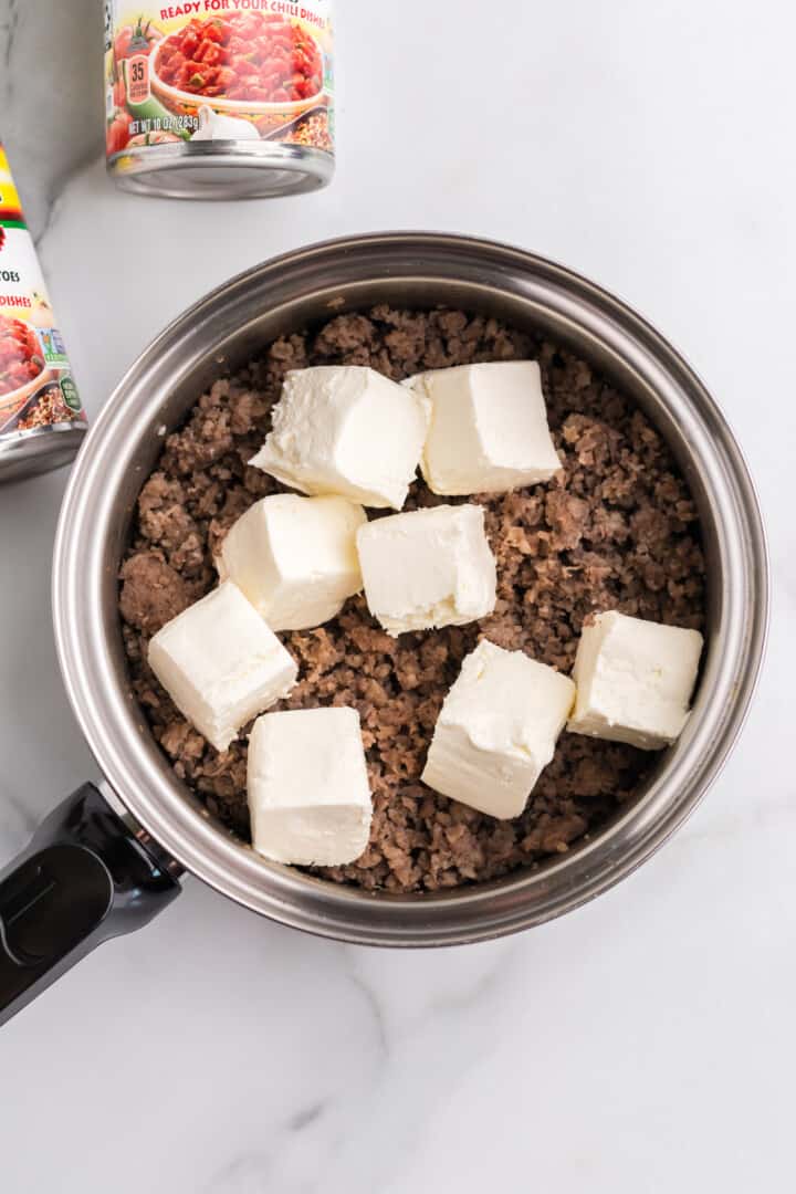 adding cream cheese to the cooked sausage.