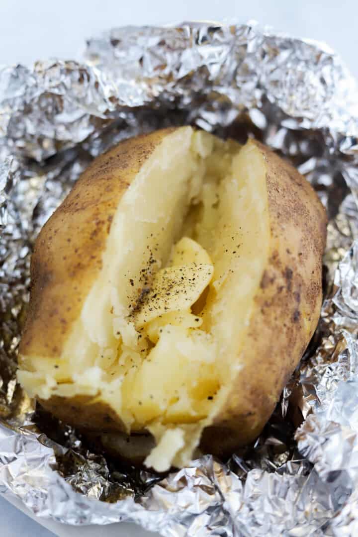 baked potato sliced in half with butter and pepper.