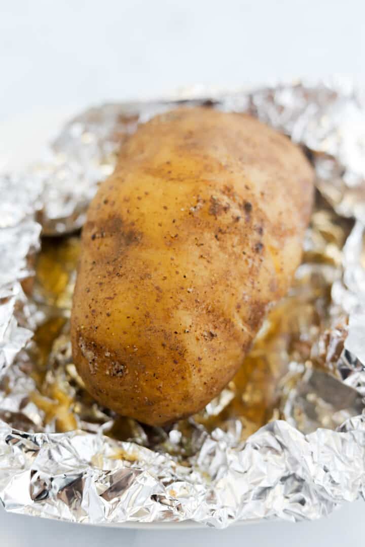 closeup of slow cooked baked potato in tin foil.