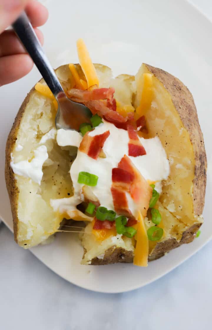 eating the baked potato with a fork.