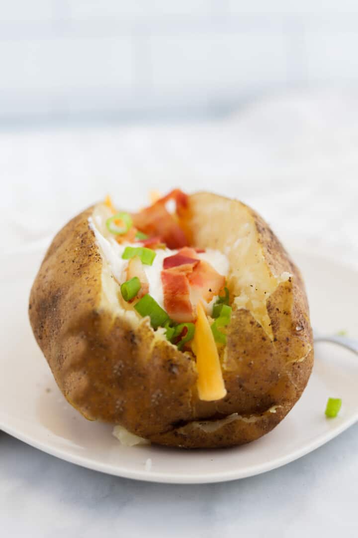 loaded baked potato with sour cream, bacon, cheese and green onions.