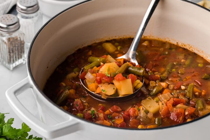 serving the vegetable soup with a ladel.