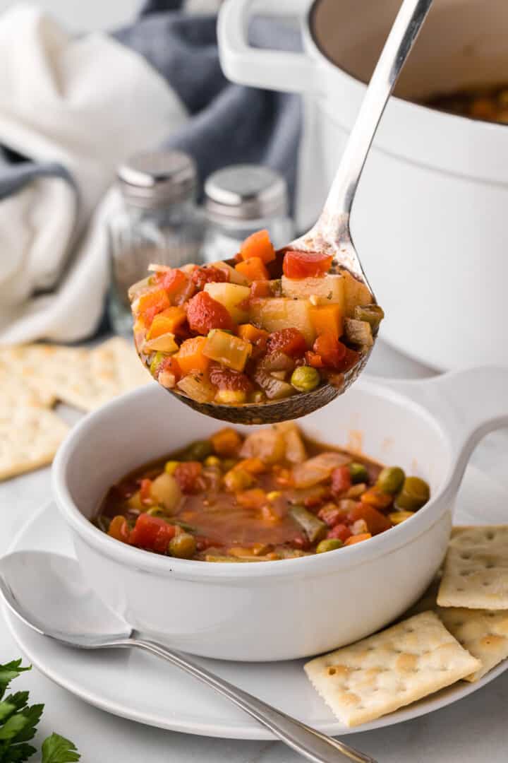 ladling the soup into a white bowl.