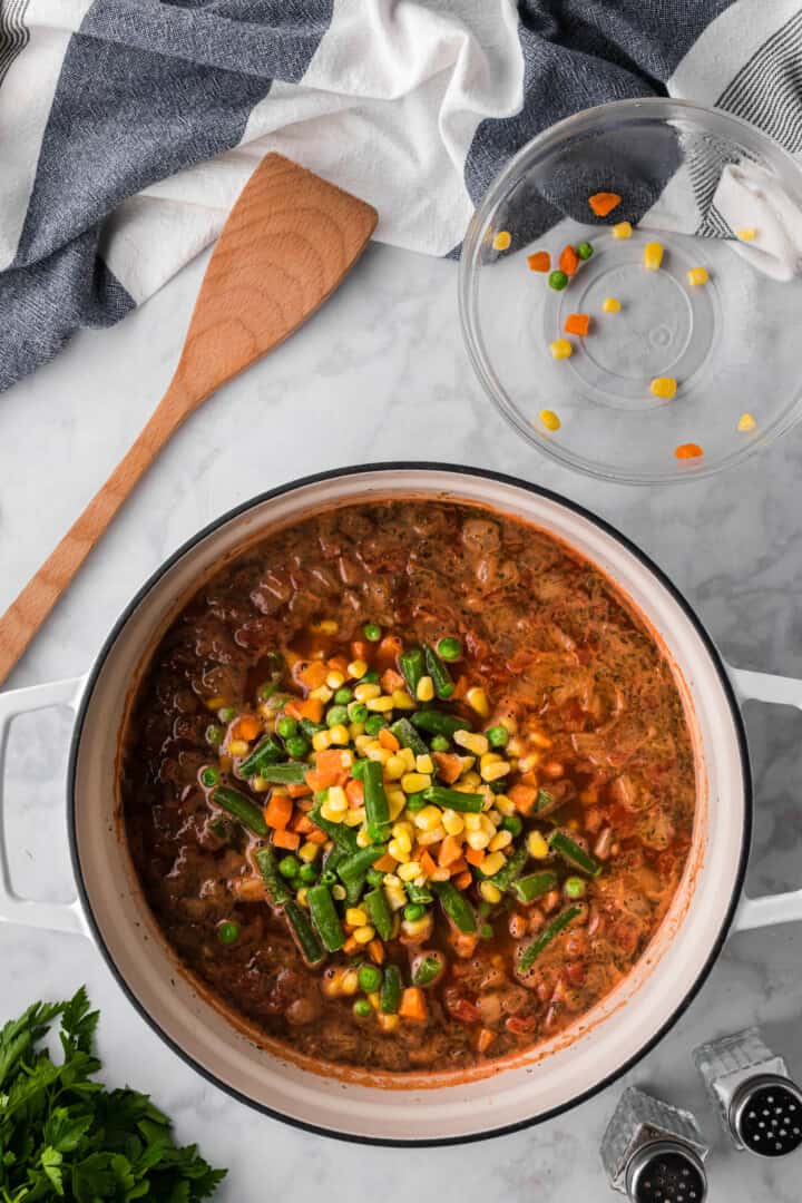 adding the frozen veggies to the soup pot.