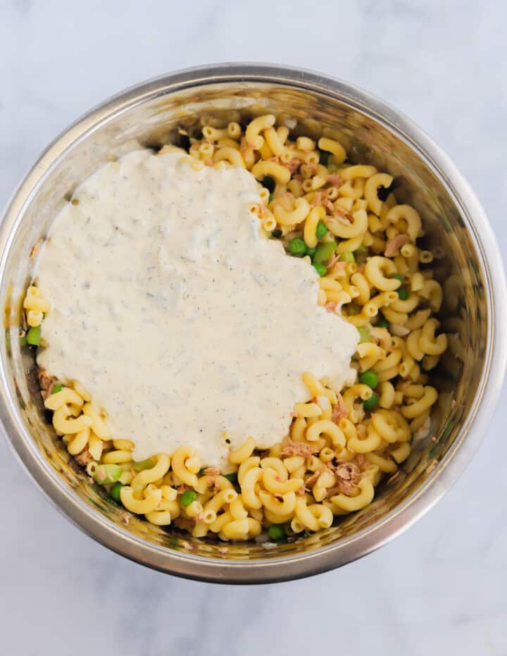 adding the dressing to the pasta salad.