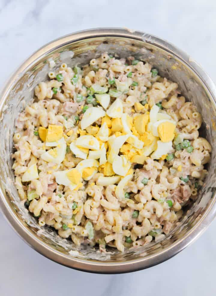 adding the hard boiled eggs to the mixed pasta salad.