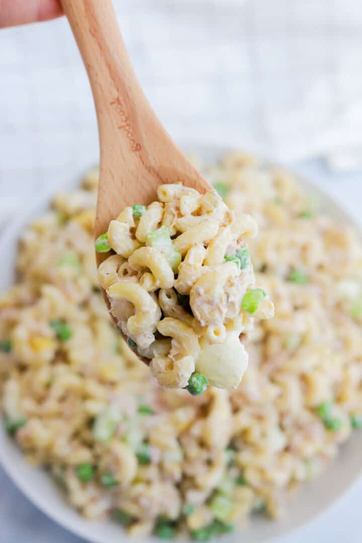 scooping the pasta salad out with a wooden spoon.