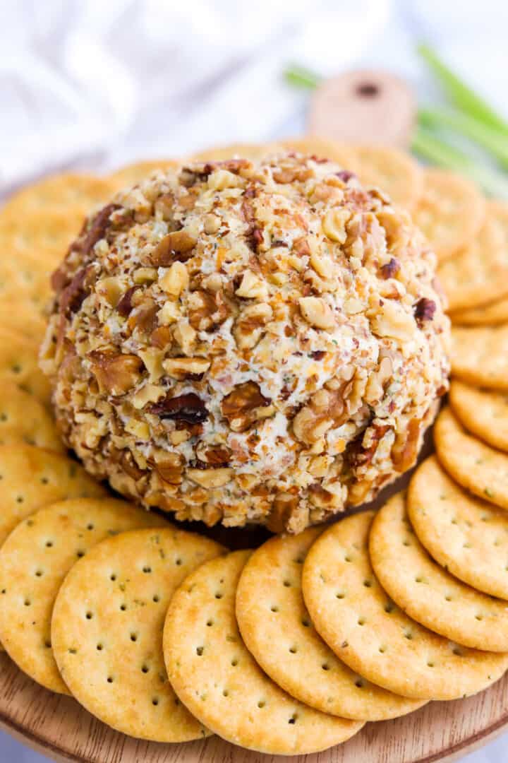 Bacon Ranch Cheese Ball on wooden serving board with crackers around it.