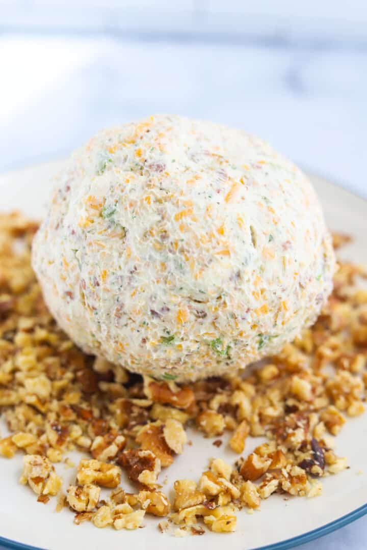 cheeseball rolled into ball on a plate of walnuts.