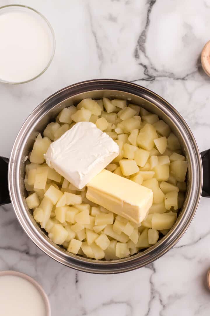 adding cream cheese and butter to the potatoes.