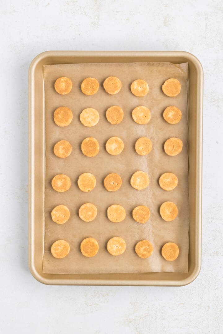 vanilla wafer cookies on baking sheet with parchment paper.