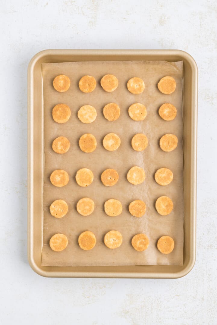 vanilla wafer cookies on baking sheet with parchment paper.