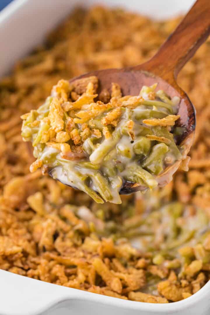 serving the green bean casserole with a wooden spoon.