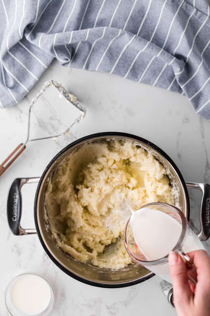 adding milk to the mashed potatoes.