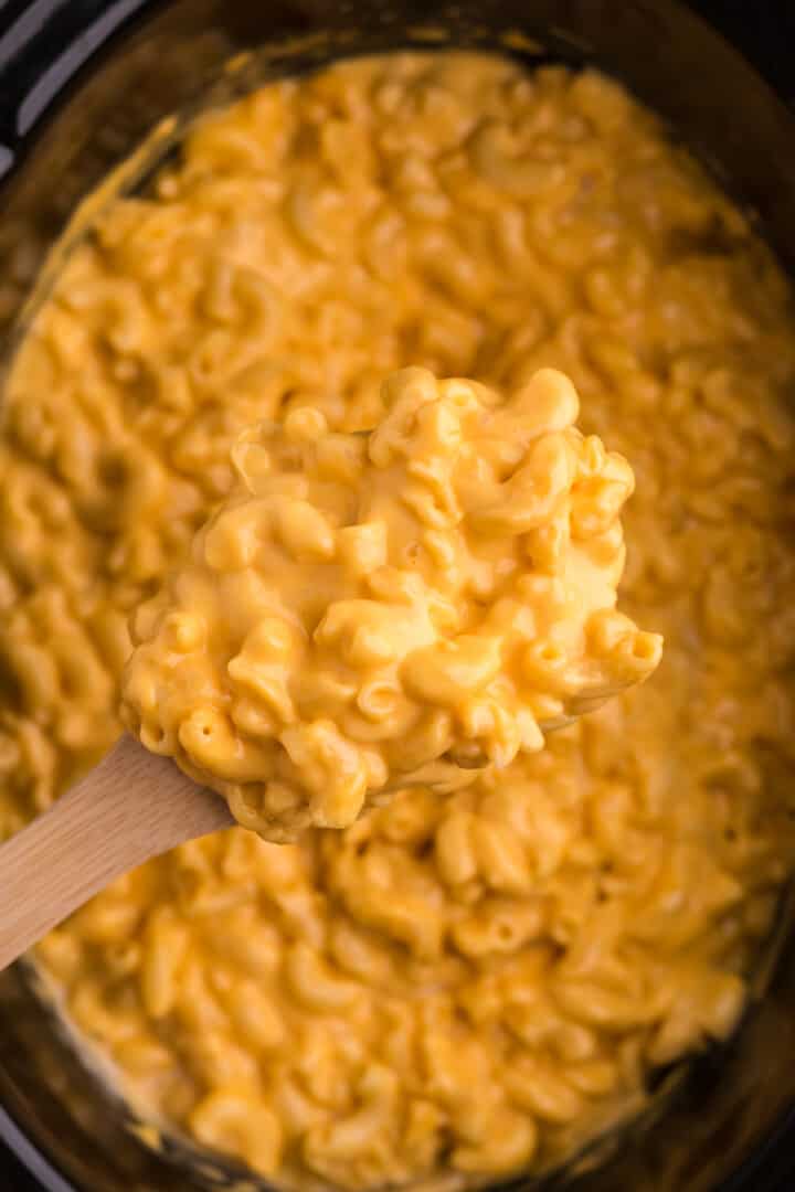 serving the mac and cheese with a wooden spoon.