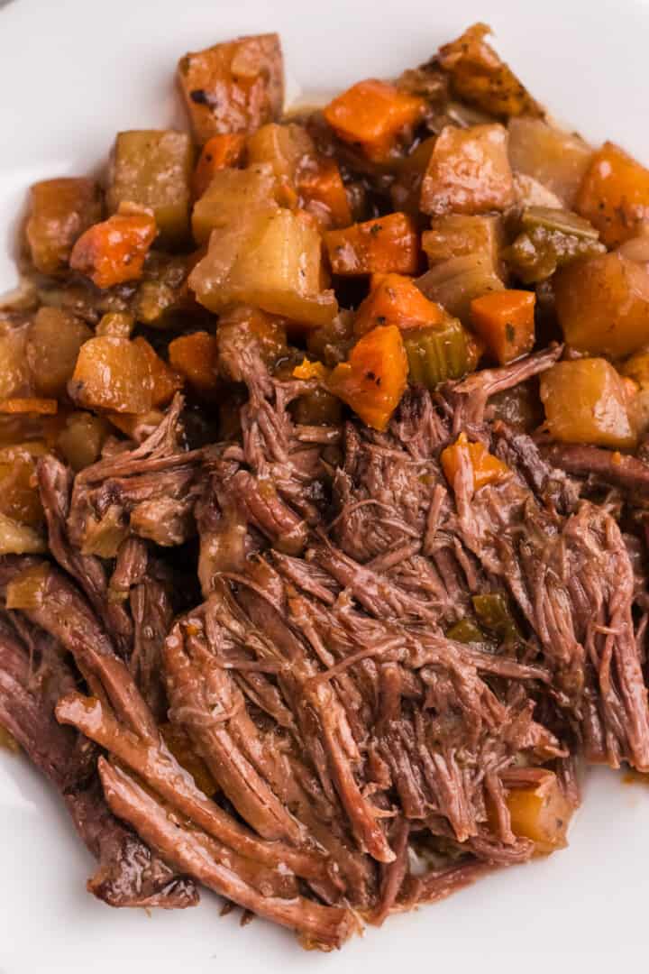 closeup of the pot roast and veggies on white plate.