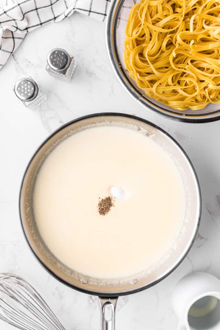 seasoning the alfredo sauce with salt and pepper.