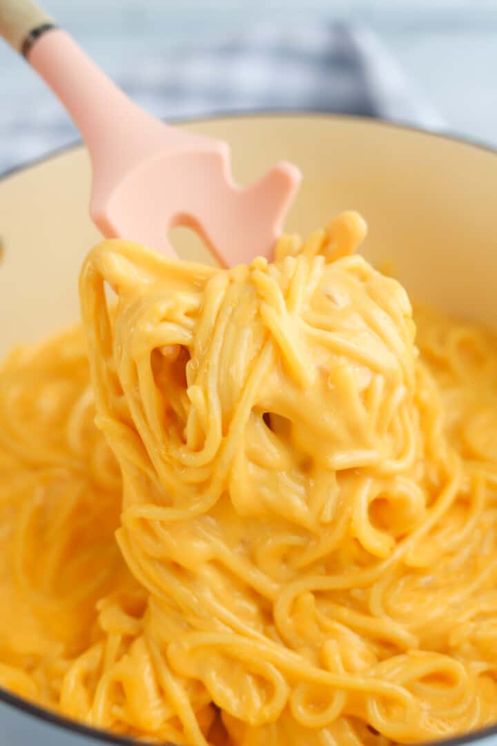 Cheesy Spaghetti being served with spaghetti tongs.