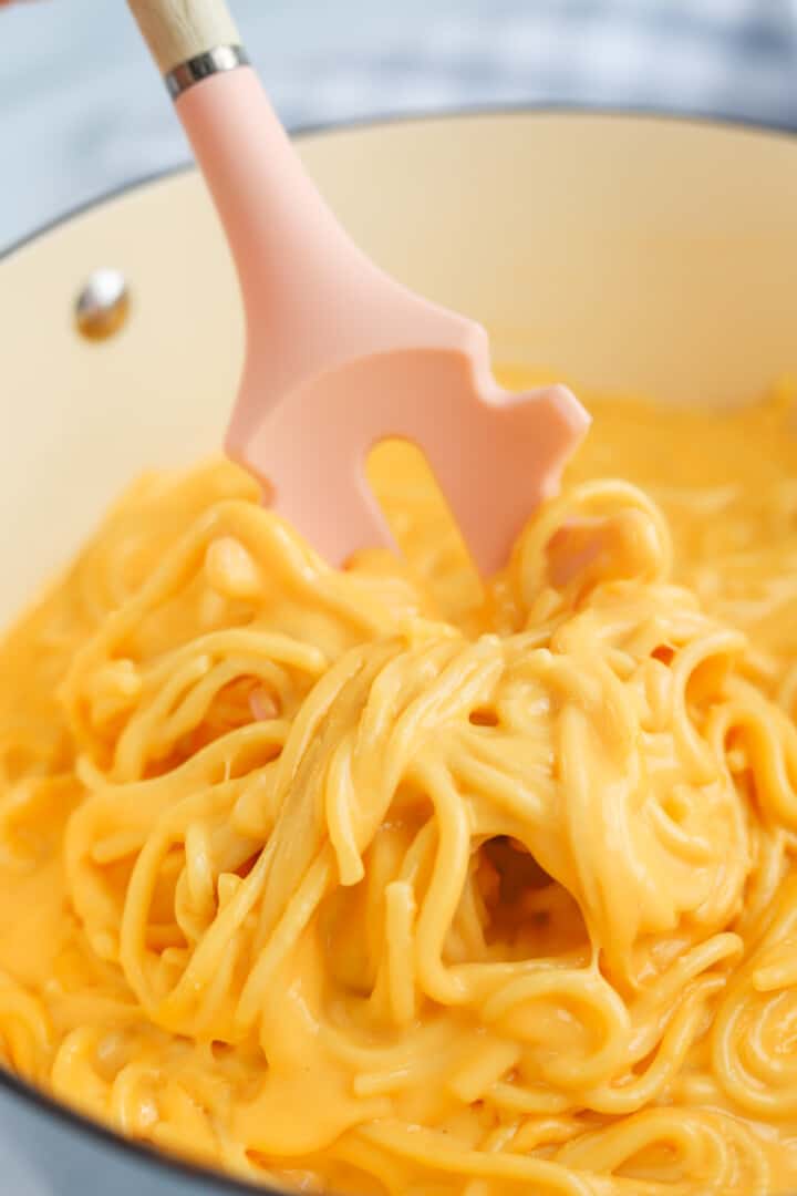 serving the cheesy spaghetti out of the pot.